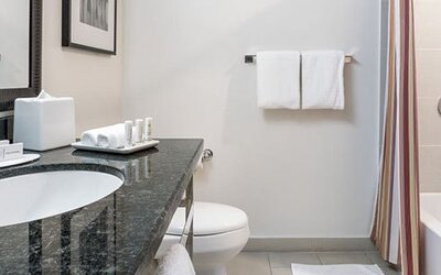 Guest bathroom at Courtyard Panama Metromall featuring a granite vanity, bathtub with shower and complimentary toiletries.