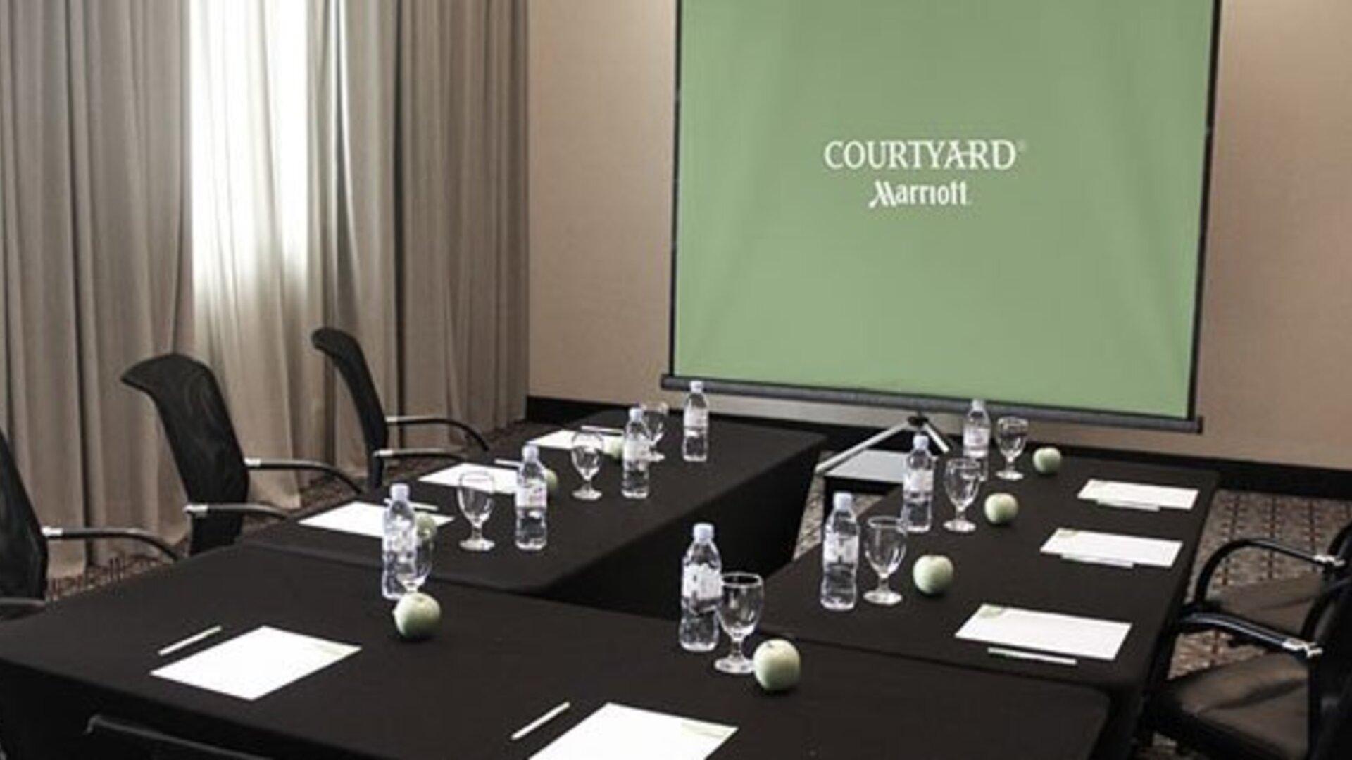 Meeting room at Courtyard Panama Metromall featuring conference tables, office chairs and a presentation screen.