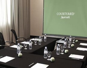 Meeting room at Courtyard Panama Metromall featuring conference tables, office chairs and a presentation screen.