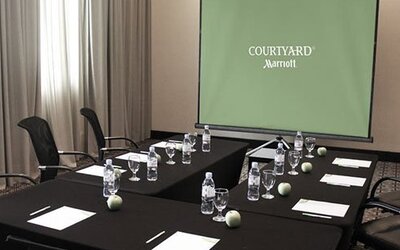 Meeting room at Courtyard Panama Metromall featuring conference tables, office chairs and a presentation screen.