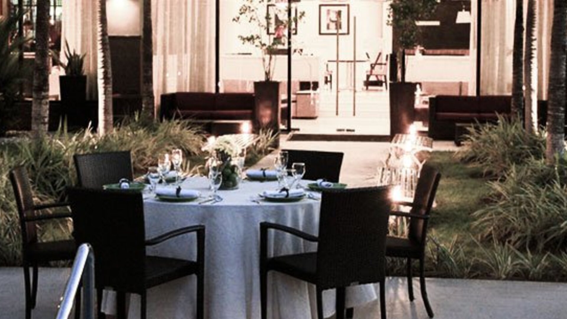 Outdoor dining area at Courtyard Panama Metromall featuring a set dining table surrounded by landscaped gardens.