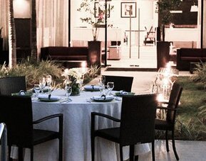 Outdoor dining area at Courtyard Panama Metromall featuring a set dining table surrounded by landscaped gardens.