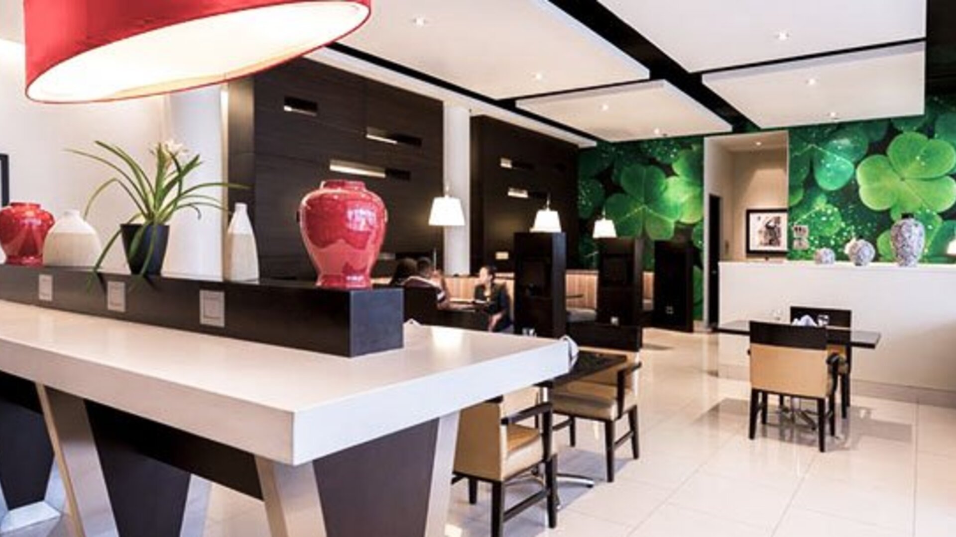 Lobby and reception area at Courtyard Panama Metromall featuring modern furnishings, decorative accents and a green feature wall.