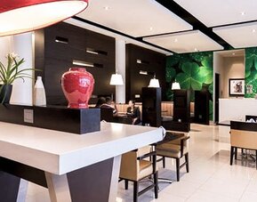 Lobby and reception area at Courtyard Panama Metromall featuring modern furnishings, decorative accents and a green feature wall.