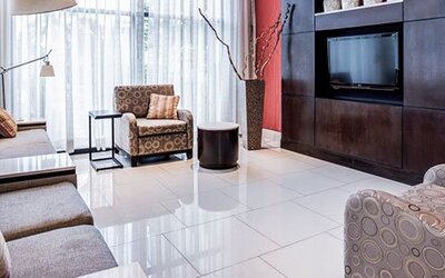 Lounge area at Courtyard Panama Metromall featuring sofas, patterned armchairs, modern lighting and a wall-mounted television.