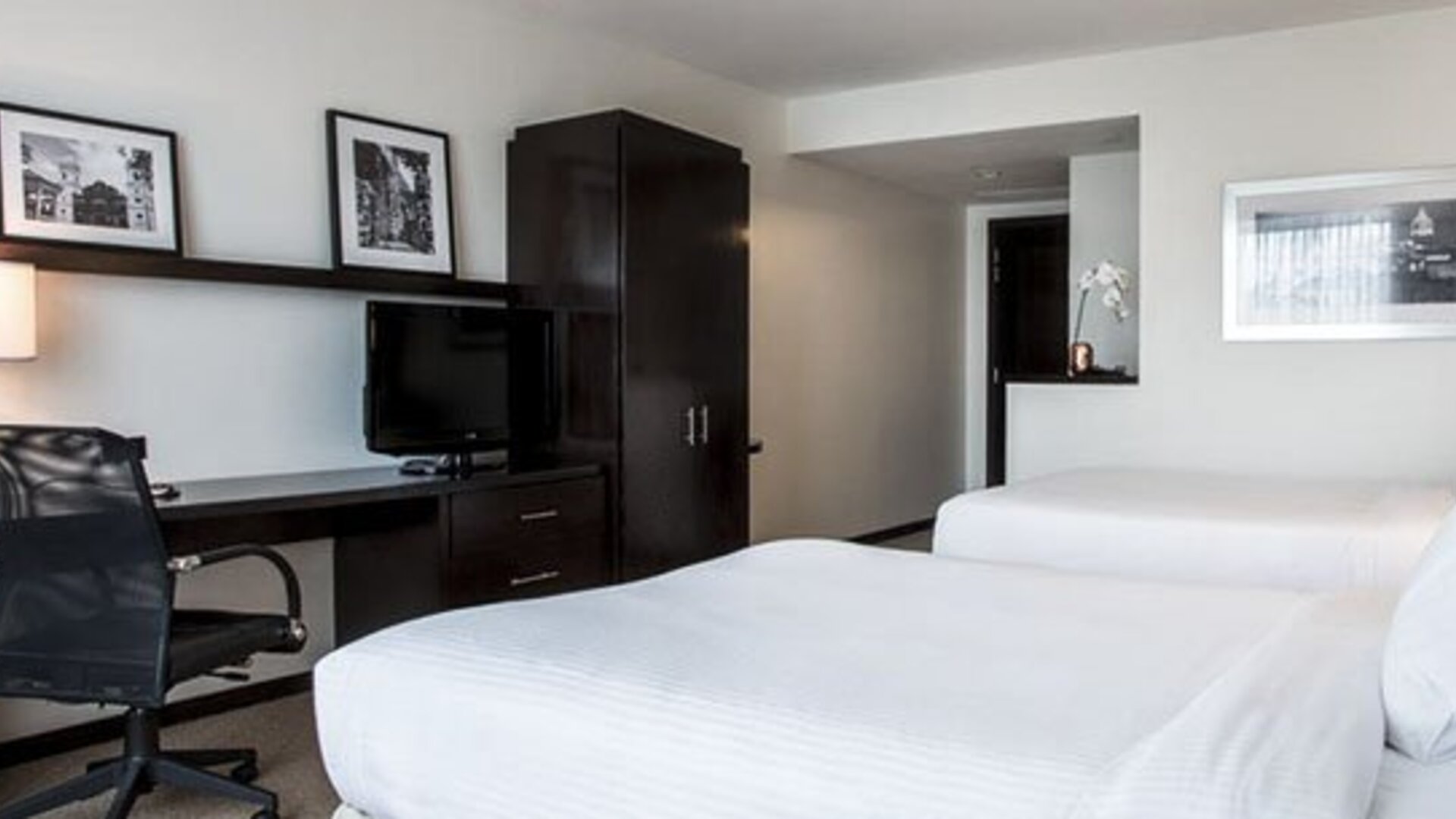 Double guest room at Courtyard Panama Metromall featuring two beds, a work desk, television and dark wood furnishings.