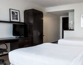 Double guest room at Courtyard Panama Metromall featuring two beds, a work desk, television and dark wood furnishings.