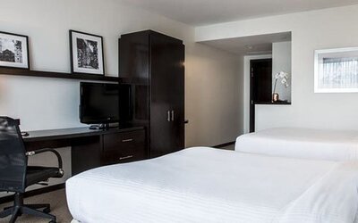 Double guest room at Courtyard Panama Metromall featuring two beds, a work desk, television and dark wood furnishings.