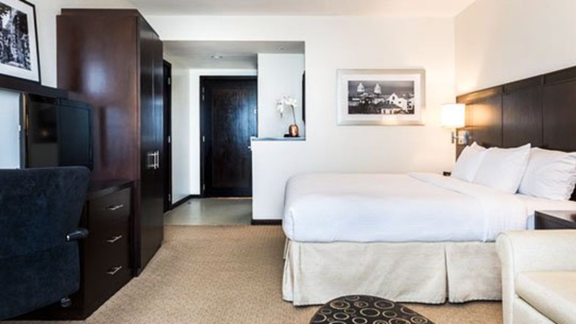 Spacious guest room at Courtyard Panama Metromall featuring a king bed, work area, television and sofa seating.