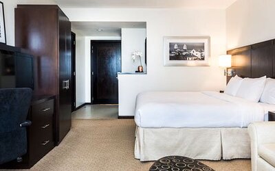 Spacious guest room at Courtyard Panama Metromall featuring a king bed, work area, television and sofa seating.