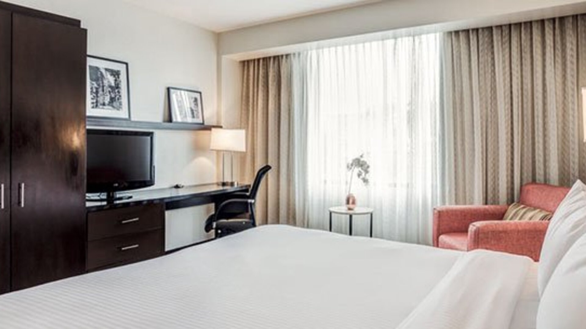 Guest room at Courtyard Panama Metromall featuring a king bed, television, work desk, wardrobe and comfortable armchair.
