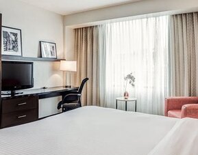 Guest room at Courtyard Panama Metromall featuring a king bed, television, work desk, wardrobe and comfortable armchair.