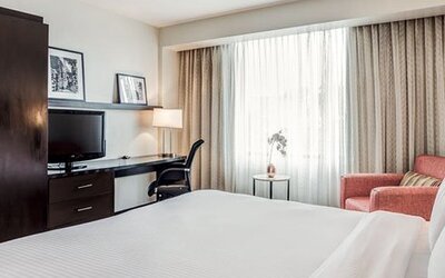 Guest room at Courtyard Panama Metromall featuring a king bed, television, work desk, wardrobe and comfortable armchair.
