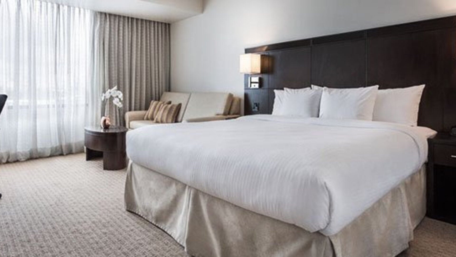 Guest room at Courtyard Panama Metromall featuring a king bed, work desk, sofa and large window with natural light.