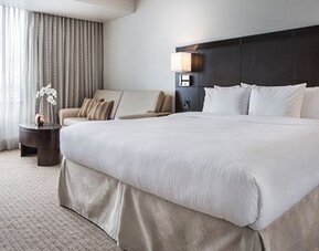 Guest room at Courtyard Panama Metromall featuring a king bed, work desk, sofa and large window with natural light.
