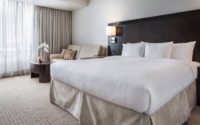 Guest room at Courtyard Panama Metromall featuring a king bed, work desk, sofa and large window with natural light.
