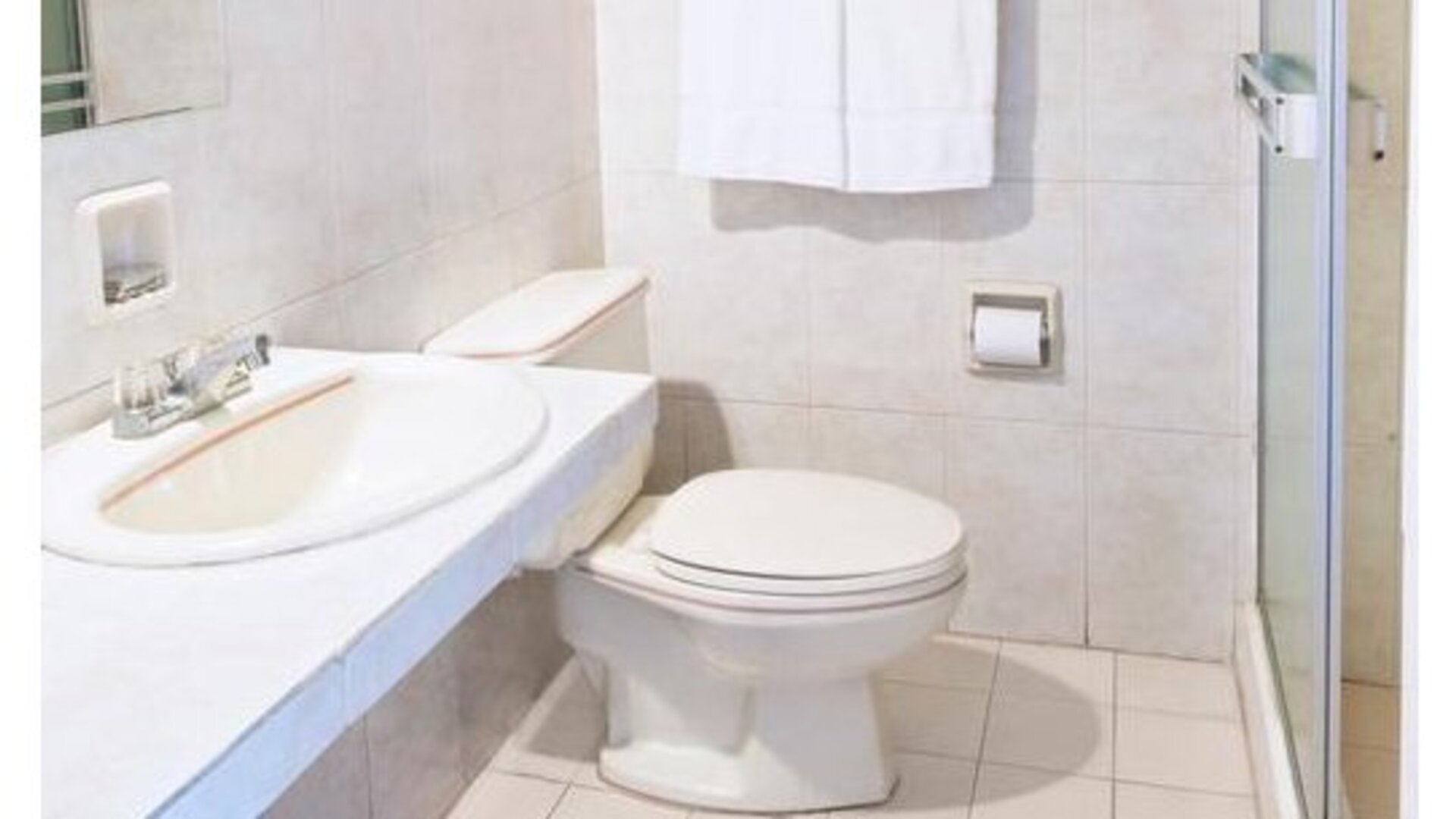 Guest bathroom at Hotel Benidorm featuring a sink, toilet and glass-enclosed shower.