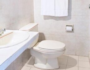 Guest bathroom at Hotel Benidorm featuring a sink, toilet and glass-enclosed shower.