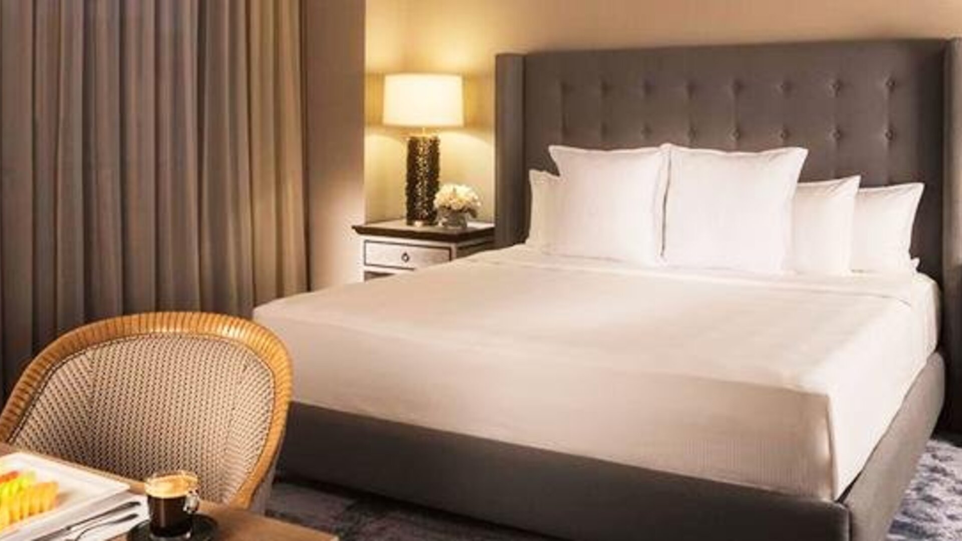 Spacious guest room at Hotel Marquis Reforma featuring a king bed, bedside lamps and a dining area.