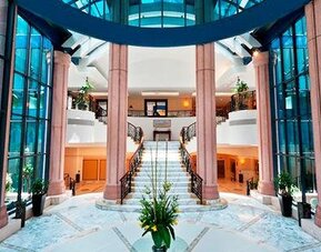 Elegant lobby at Hotel Marquis Reforma featuring blue tufted sofas, large round mirrors and modern seating.