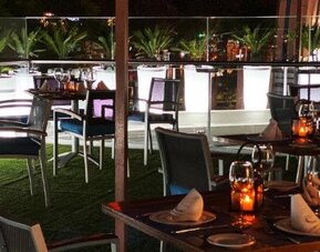 Outdoor dining terrace at Hotel Marquis Reforma featuring set tables, contemporary seating and ambient evening lighting.