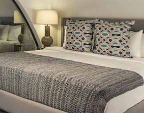 Guest room at Hotel Marquis Reforma featuring a king bed, patterned cushions, bedside lamps and contemporary furnishings.
