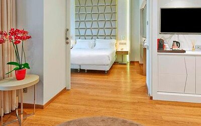 Spacious suite featuring wood flooring, a separate sleeping area, television and coffee station at NH Collection Barcelona Pódium.