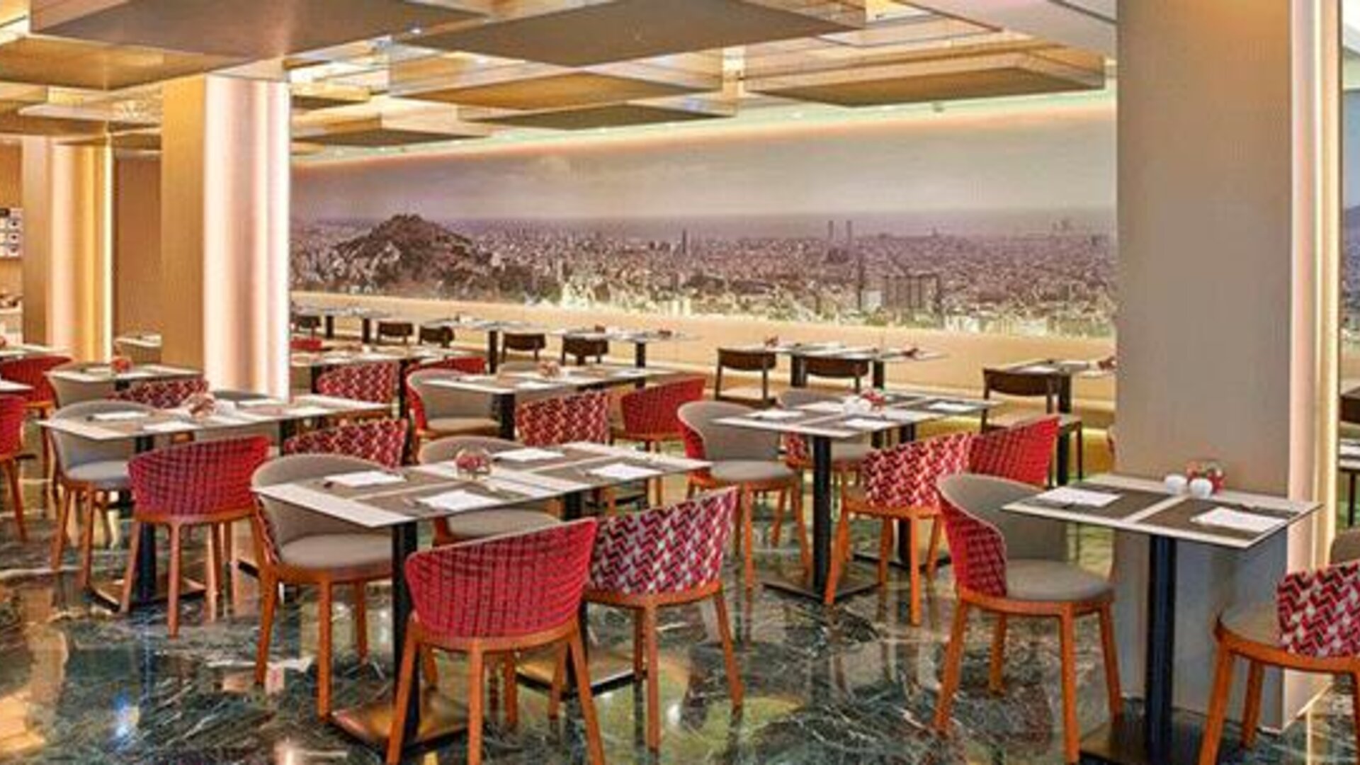 Spacious restaurant featuring dining tables, red patterned chairs and a panoramic city mural at NH Collection Barcelona Pódium.