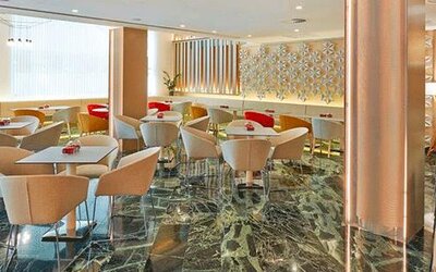 Modern dining area featuring tables, upholstered chairs and a bar counter at NH Collection Barcelona Pódium.