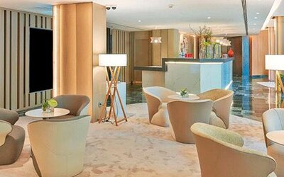 Elegant lobby seating area featuring modern armchairs, small tables and floor lamps at NH Collection Barcelona Pódium.