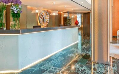 Contemporary reception desk featuring marble finishes, floral arrangements and warm lighting at NH Collection Barcelona Pódium.