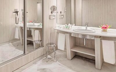 Spacious bathroom featuring a vanity, large mirrors, wall-mounted hairdryer and contemporary finishes at NH Collection Barcelona Pódium.