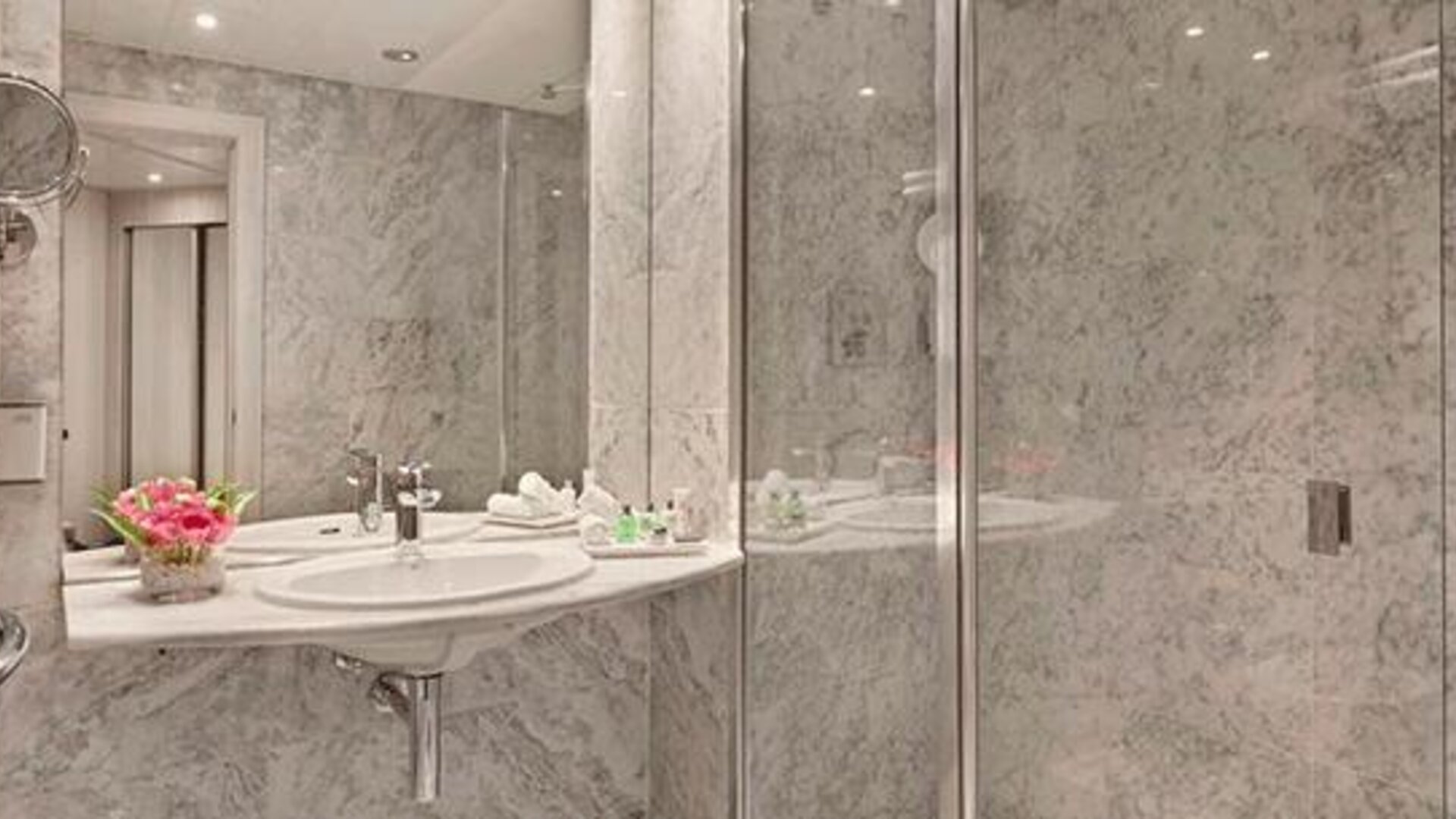 Marble bathroom featuring a sink, large mirror and glass-enclosed shower at NH Collection Barcelona Pódium.
