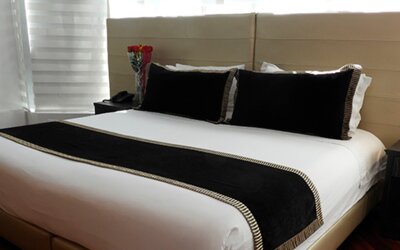 Guest room featuring a king bed, black accent cushions, bedside tables and contemporary lighting at Hotel Airport Travel.
