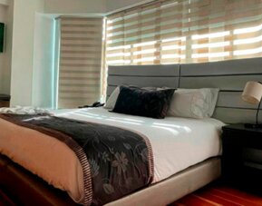 Modern guest room featuring a king bed, work desk, large windows and polished wood flooring at Hotel Airport Travel.