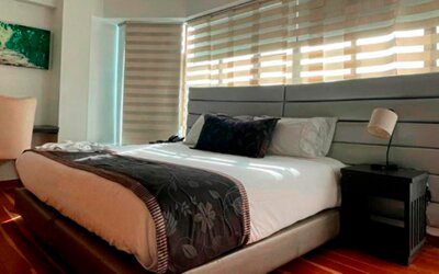 Modern guest room featuring a king bed, work desk, large windows and polished wood flooring at Hotel Airport Travel.