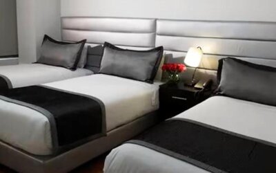 Guest room featuring three beds, coordinated black-and-white bedding and bedside lighting at Hotel Airport Travel.