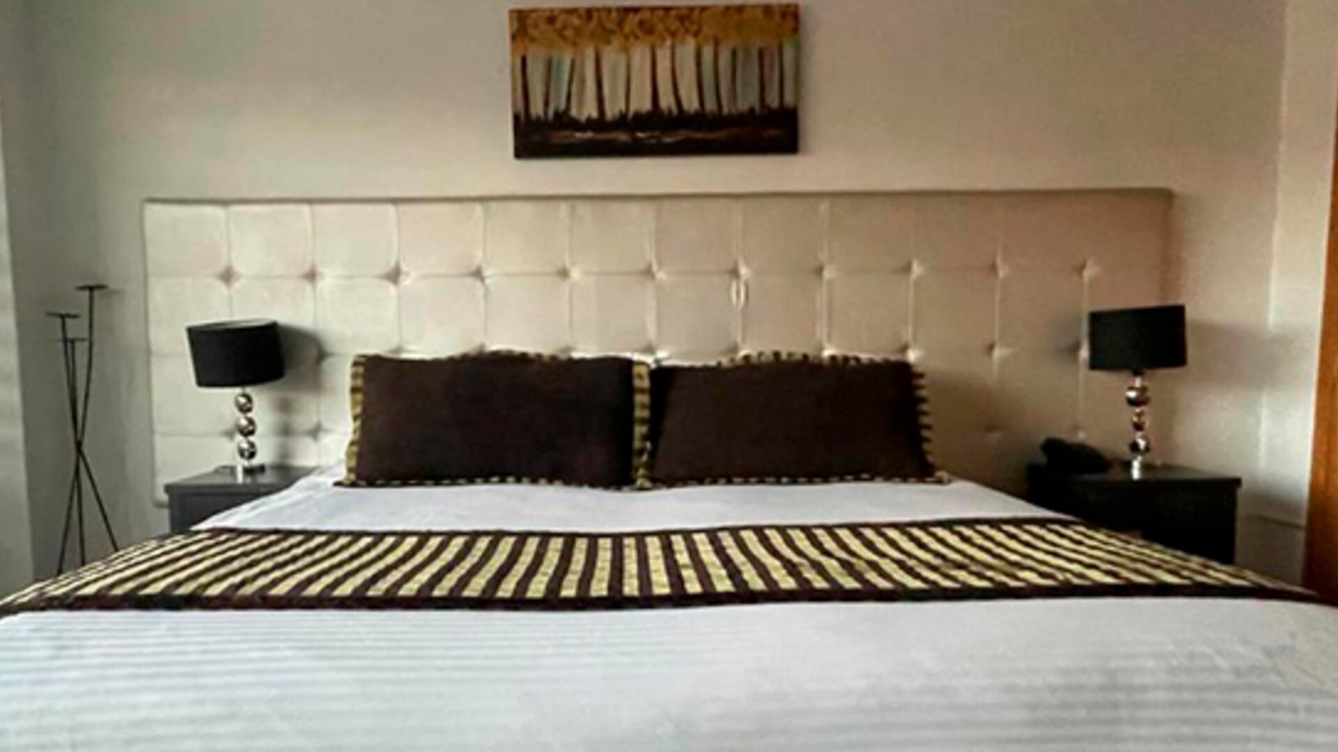 Guest room featuring a king bed, padded headboard, bedside lamps and contemporary décor at Hotel Airport Travel.