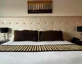 Guest room featuring a king bed, padded headboard, bedside lamps and contemporary décor at Hotel Airport Travel.