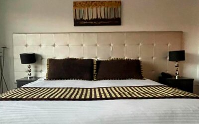 Guest room featuring a king bed, padded headboard, bedside lamps and contemporary décor at Hotel Airport Travel.