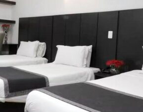 Guest room featuring three beds, dark upholstered headboards and contemporary black-and-white bedding at Hotel Airport Travel.