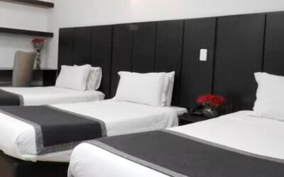 Guest room featuring three beds, dark upholstered headboards and contemporary black-and-white bedding at Hotel Airport Travel.