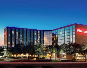 Modern hotel exterior featuring illuminated signage, contemporary architecture and landscaped grounds at Sheraton Houston Brookhollow Hotel.