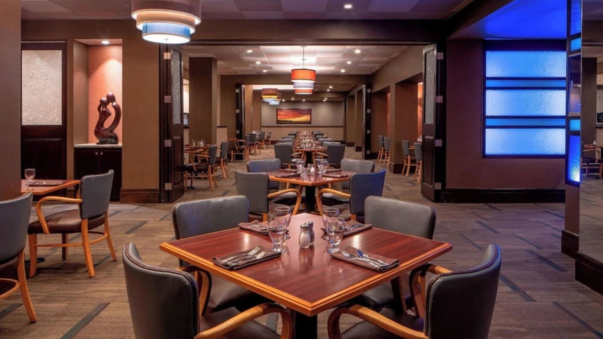 Modern restaurant featuring wood furnishings, ambient lighting and an open dining layout at Sheraton Houston Brookhollow Hotel.