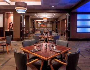 Modern restaurant featuring wood furnishings, ambient lighting and an open dining layout at Sheraton Houston Brookhollow Hotel.