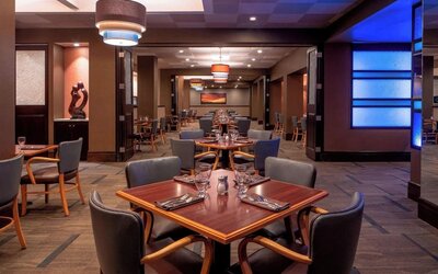 Modern restaurant featuring wood furnishings, ambient lighting and an open dining layout at Sheraton Houston Brookhollow Hotel.