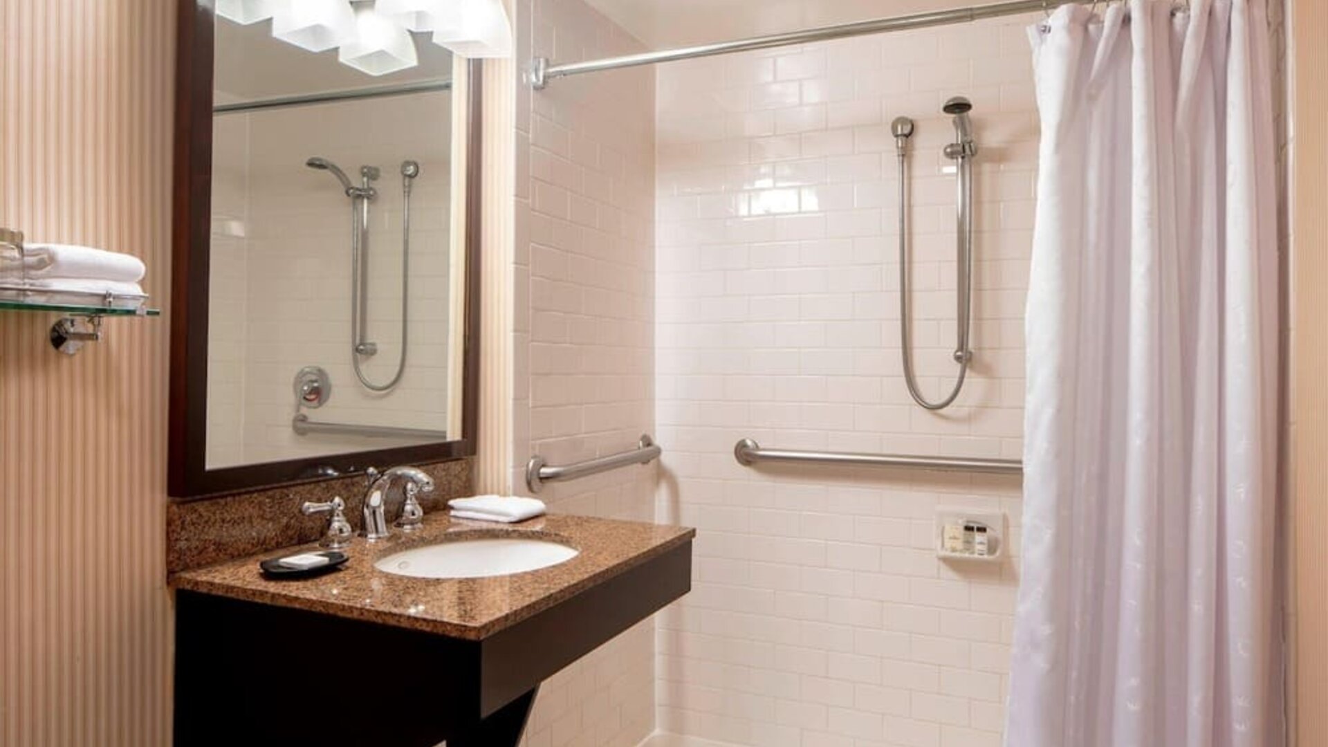 Accessible bathroom featuring a roll-in shower, safety grab bars and a granite vanity at Sheraton Houston Brookhollow Hotel.
