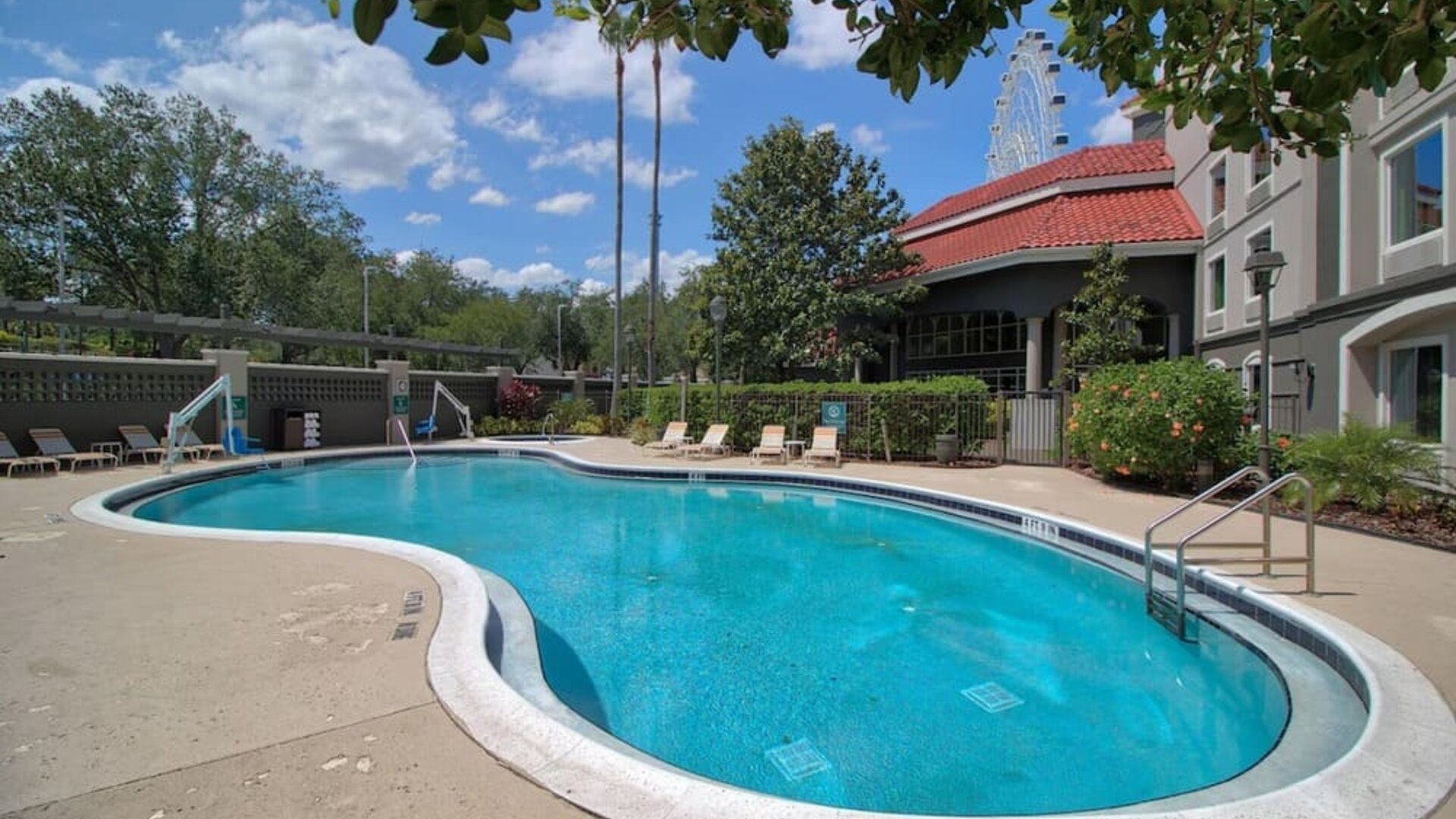 Outdoor swimming pool featuring a curved design, surrounding sun loungers and landscaped grounds at La Quinta Inn & Suites By Wyndham Orlando I Drive/Conv Ctr.