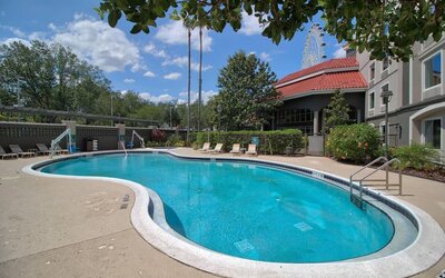 Outdoor swimming pool featuring a curved design, surrounding sun loungers and landscaped grounds at La Quinta Inn & Suites By Wyndham Orlando I Drive/Conv Ctr.