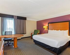 Contemporary guest room featuring a king-size bed, a spacious work area and modern furnishings at La Quinta Inn & Suites By Wyndham Orlando I Drive/Conv Ctr.